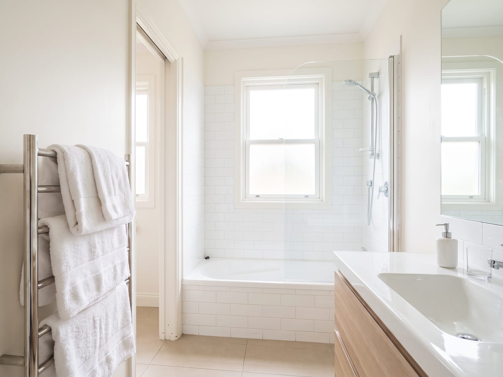 Bathroom after a clean, shower glass dried free of water spots and towels folded on the rail