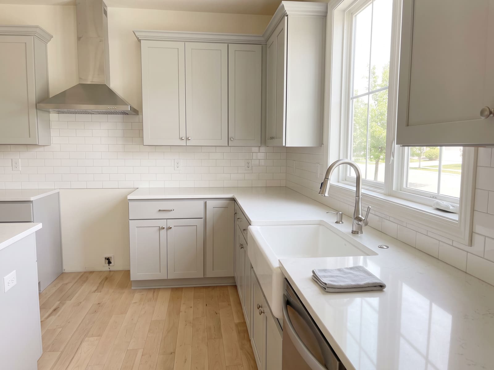 Kitchen after a deep clean, quartz counters cleared and the stainless faucet and range hood polished